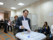 Алексей Гордеев отпускают бюллетень в урну для голосования.