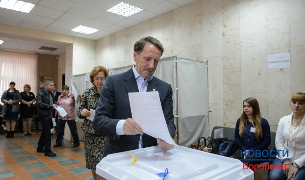 Алексей Гордеев отпускают бюллетень в урну для голосования.