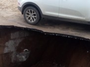 Асфальт провалился рядом со стоящей иномаркой.