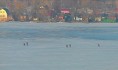 Рыбаки сидят на льду у открытой воды.