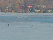 Рыбаки сидят на льду у открытой воды.