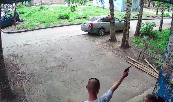 Воронежец стреляет из пистолета во дворе дома.