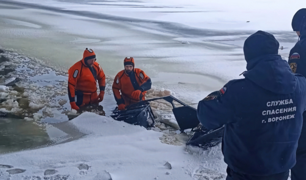 Спасатели вытаскивают из-под воды снегоход.