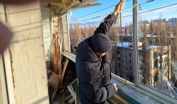 Работники ведут замеры окон.